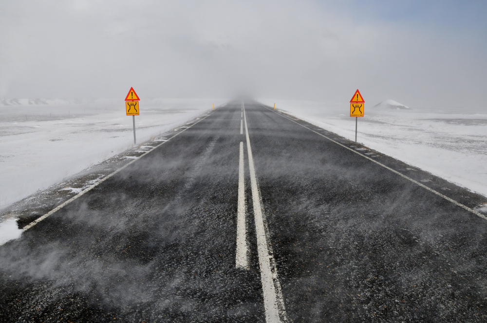 Una de las carreteras que se encuentran abiertas en invierno en Islandia carretera con niebla y nieve al rededor y carteles de peligro al conducir en invierno por islandia