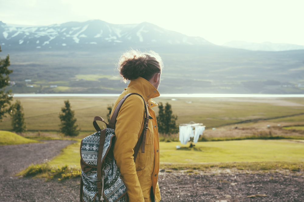 Girl with a yellow jacket looking at the green pastures of Iceland in June
