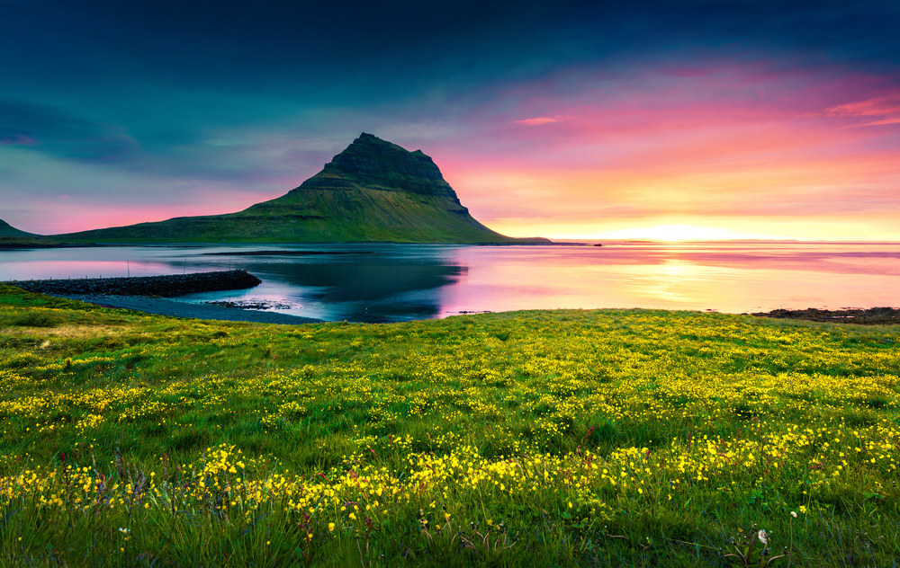 Kirkjufell mountain with a setting sun on the horizon of a beautiful june day in iceland