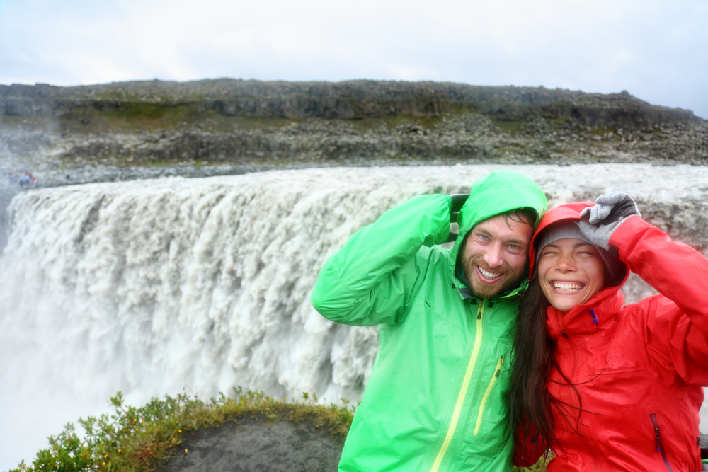 Pareja con chubasqueros para el tiempo húmedo en octubre en Islandia